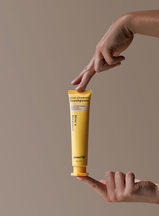 yellow tube of About28 toothpaste held between two fingers