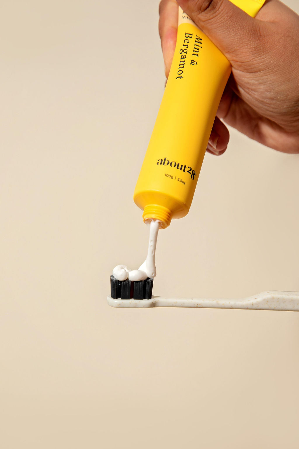 about28 natural hydroxyapatite toothpaste being dispensed onto a white toothbrush with black bristles